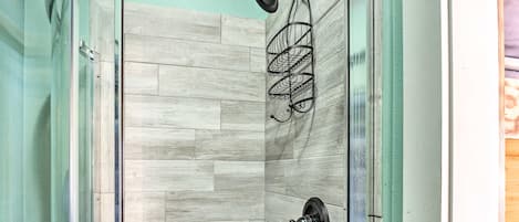 A shower area with a wooden floor and a glass door.