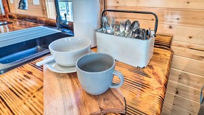 A wooden kitchen counter with a sink, two white bowls, a white pitcher, and a utensil holder. - Sunny 'catfish Cabin' w/ Views of Toledo Bend (Many)