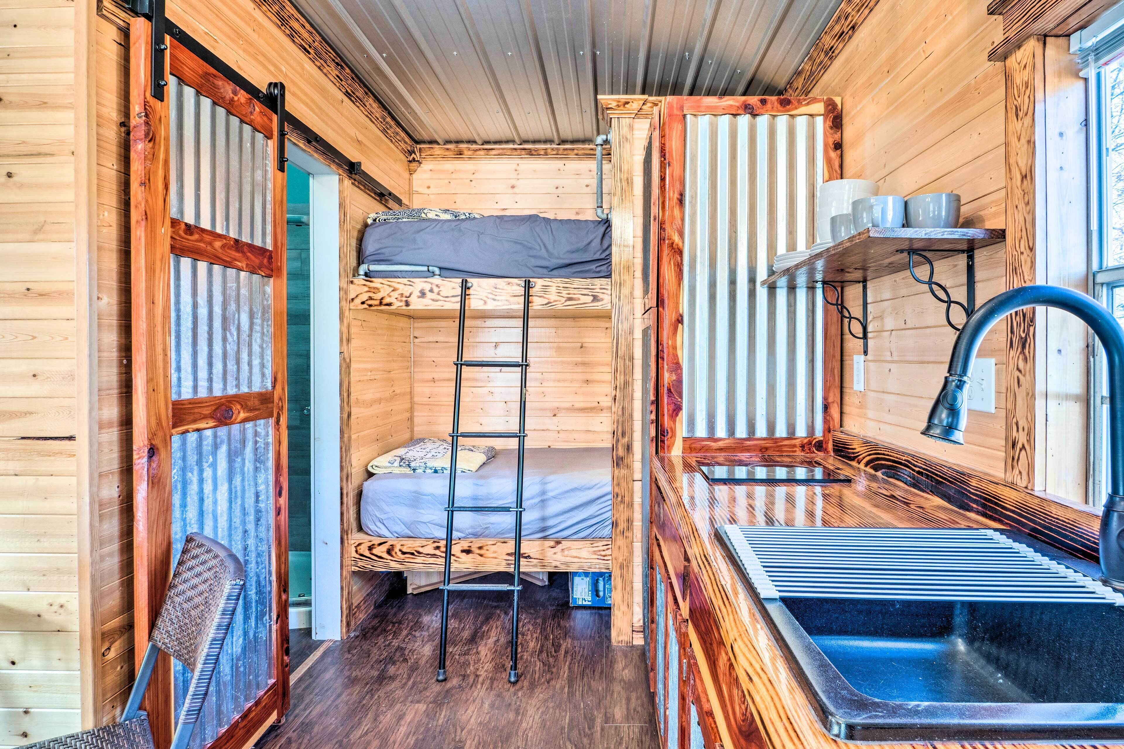 A compact cabin with a bunk bed, a small sink, and a chair.