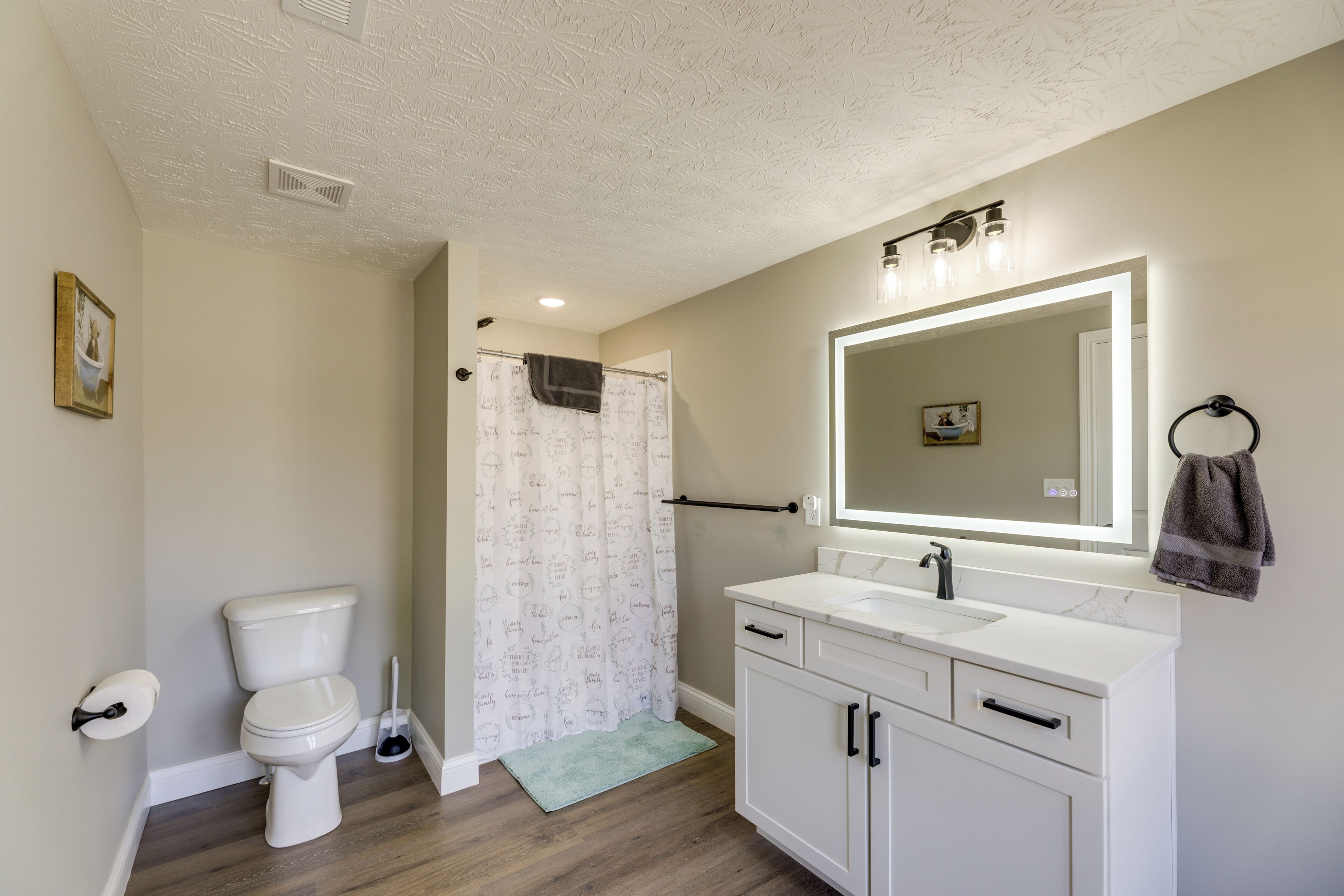 A bathroom with a toilet, sink, mirror, and shower curtain.