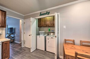 A laundry room with wooden cabinets, a washing machine, a dryer, and a table with chairs.