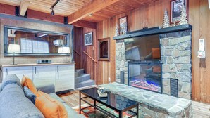 Un salon chaleureux avec une cheminée en pierre, un plafond en bois et un canapé moderne.