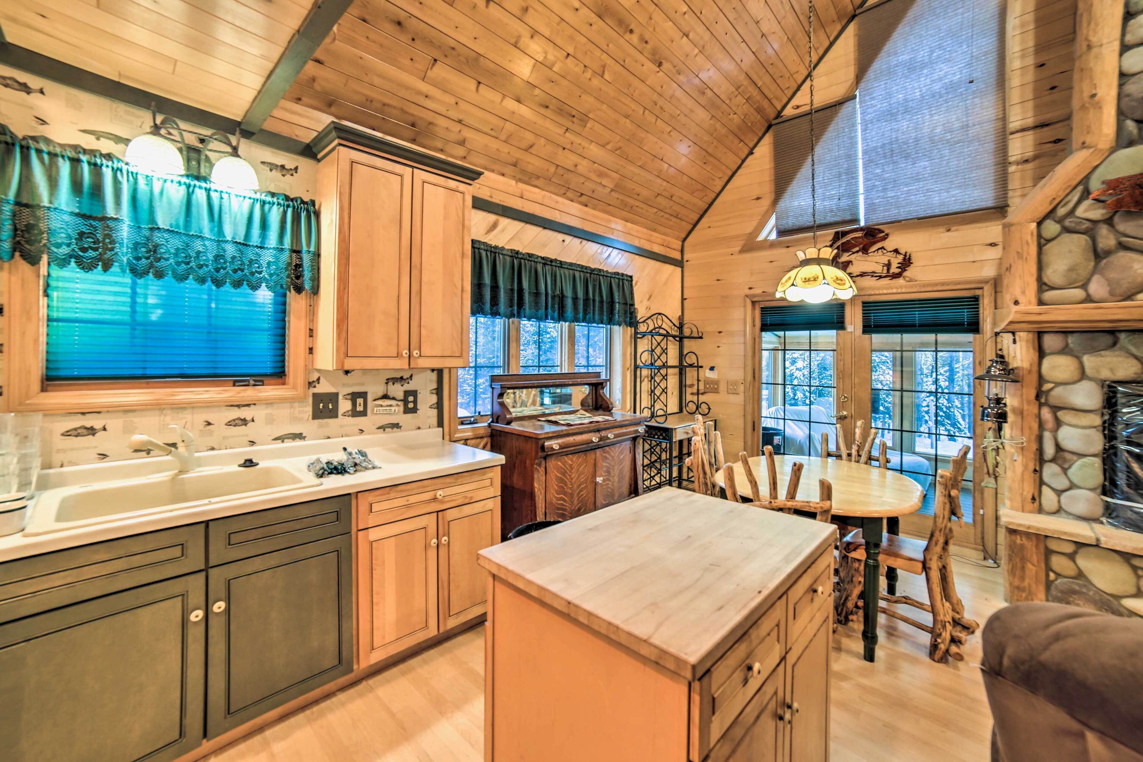 A rustic kitchen with wooden cabinets, a large island, and a dining area with wooden chairs.