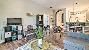 Ein modernes Wohnzimmer mit Fernseher, Sitzgelegenheiten und einem Essbereich.