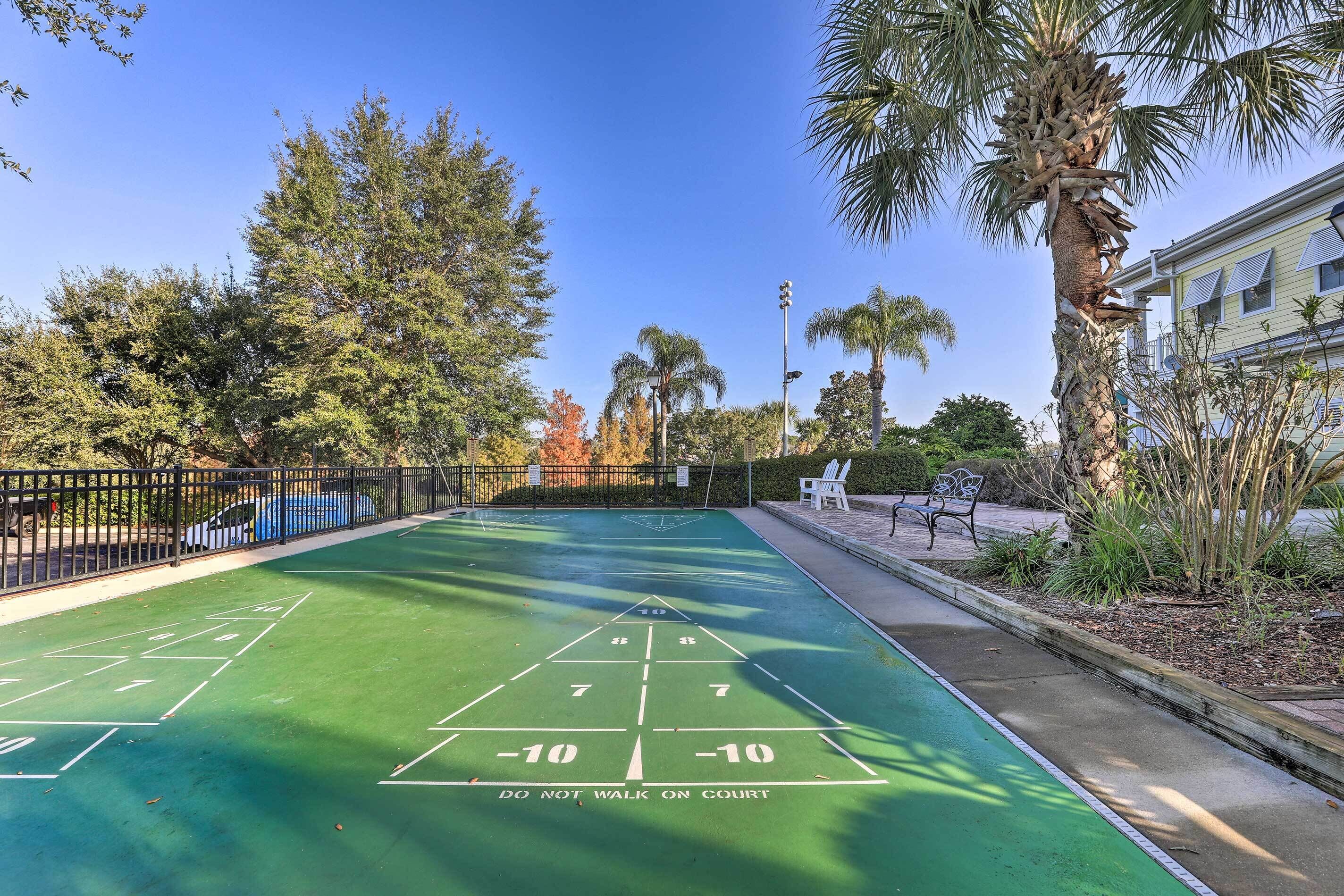 A shuffleboard court with a 'DO NOT WALK ON COURT' sign, surrounded by trees and a building.