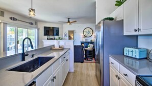 A modern kitchen with a large island, built-in appliances, and a view to the outside.