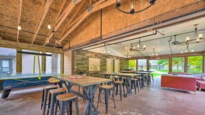 Un vaste espace intérieur doté de hauts plafonds, de poutres apparentes en bois et de nombreuses tables et tabourets.