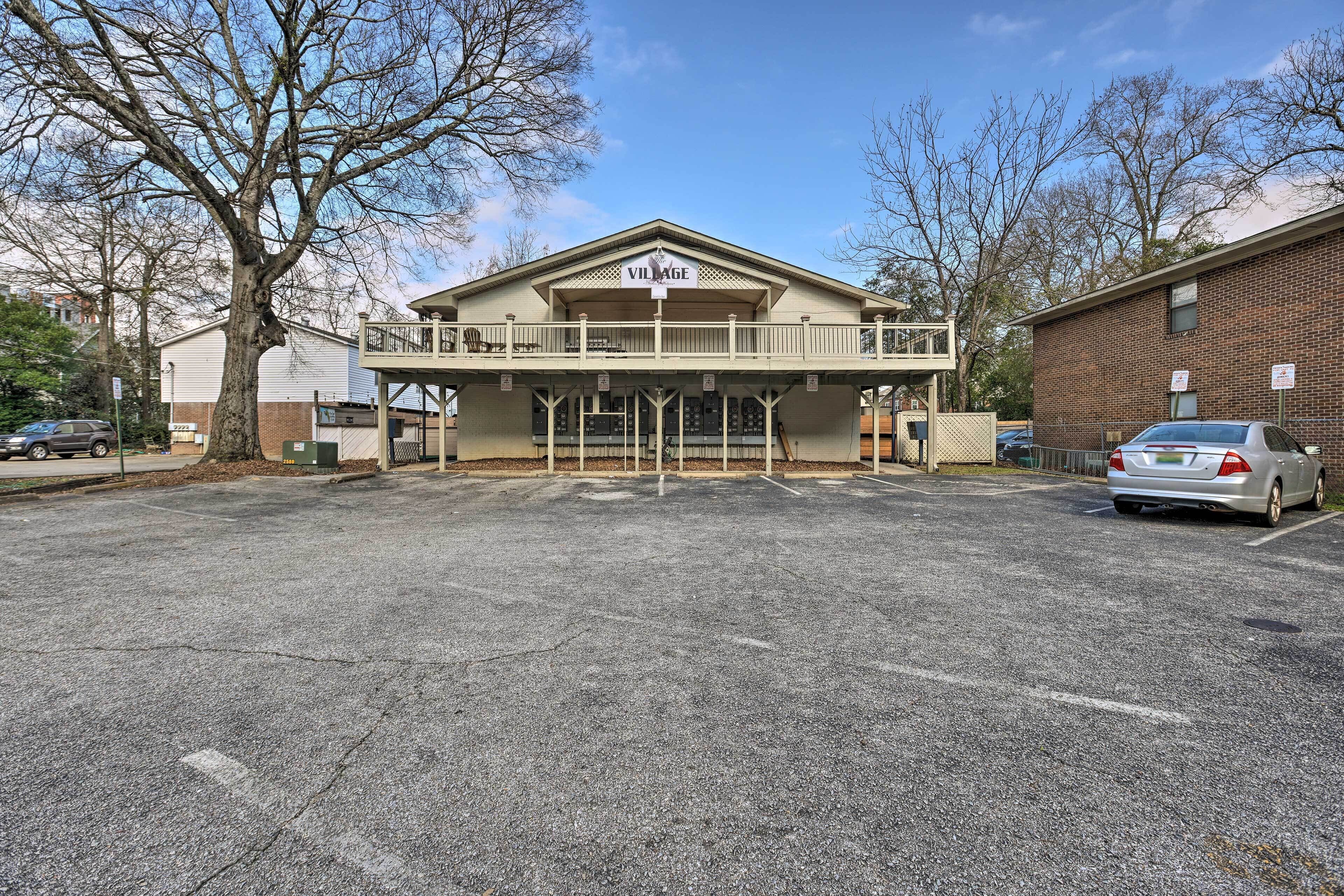 A building labeled "VILLAGE" with a balcony, parking lot, and a tree in the foreground.