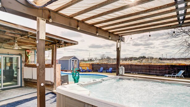 Un espace extérieur abrité avec une piscine, un jacuzzi, des chaises longues et un petit bâtiment en arrière-plan.