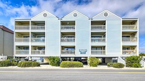 A multi-story hotel with balconies, a sign reading "Madin's Way," and a parking area in front.