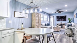 A modern kitchen with a central island, white cabinetry, and a dining area with a round table and chairs.