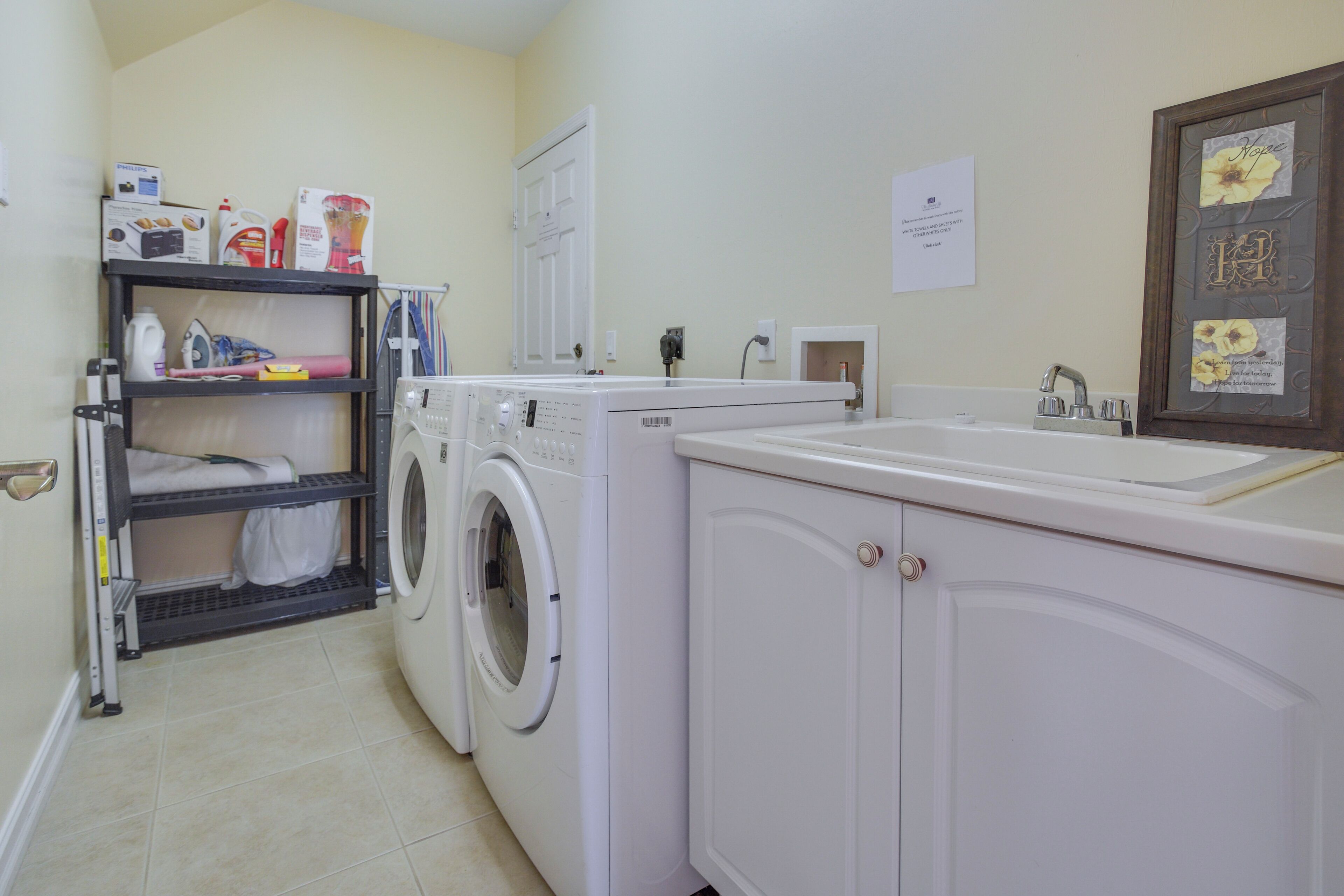 A laundry room with a washing machine, dryer, and shelves with cleaning supplies.