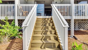 A wooden staircase leading to a building with white railings and a covered entrance. - Harbor Island Condo w/ Pool Access: Walk to Beach! (Harbor Island)