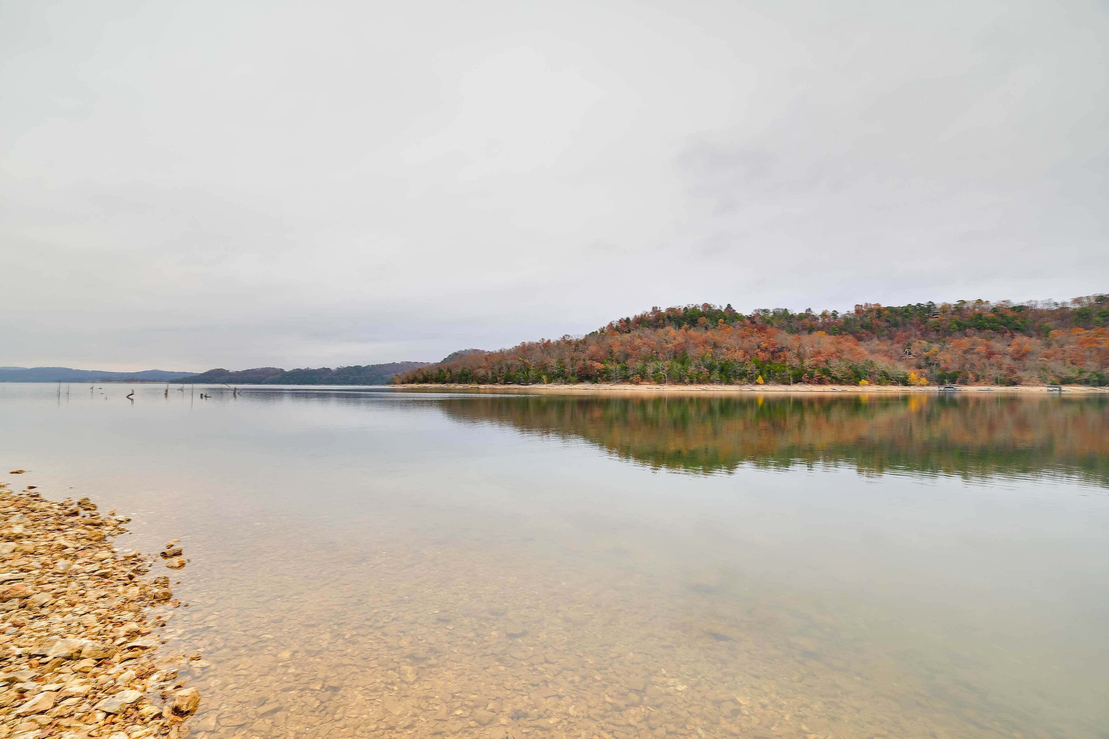 Un llac tranquil amb aigües cristal·lines que reflecteixen els arbres circumdants i una riba llunyana.