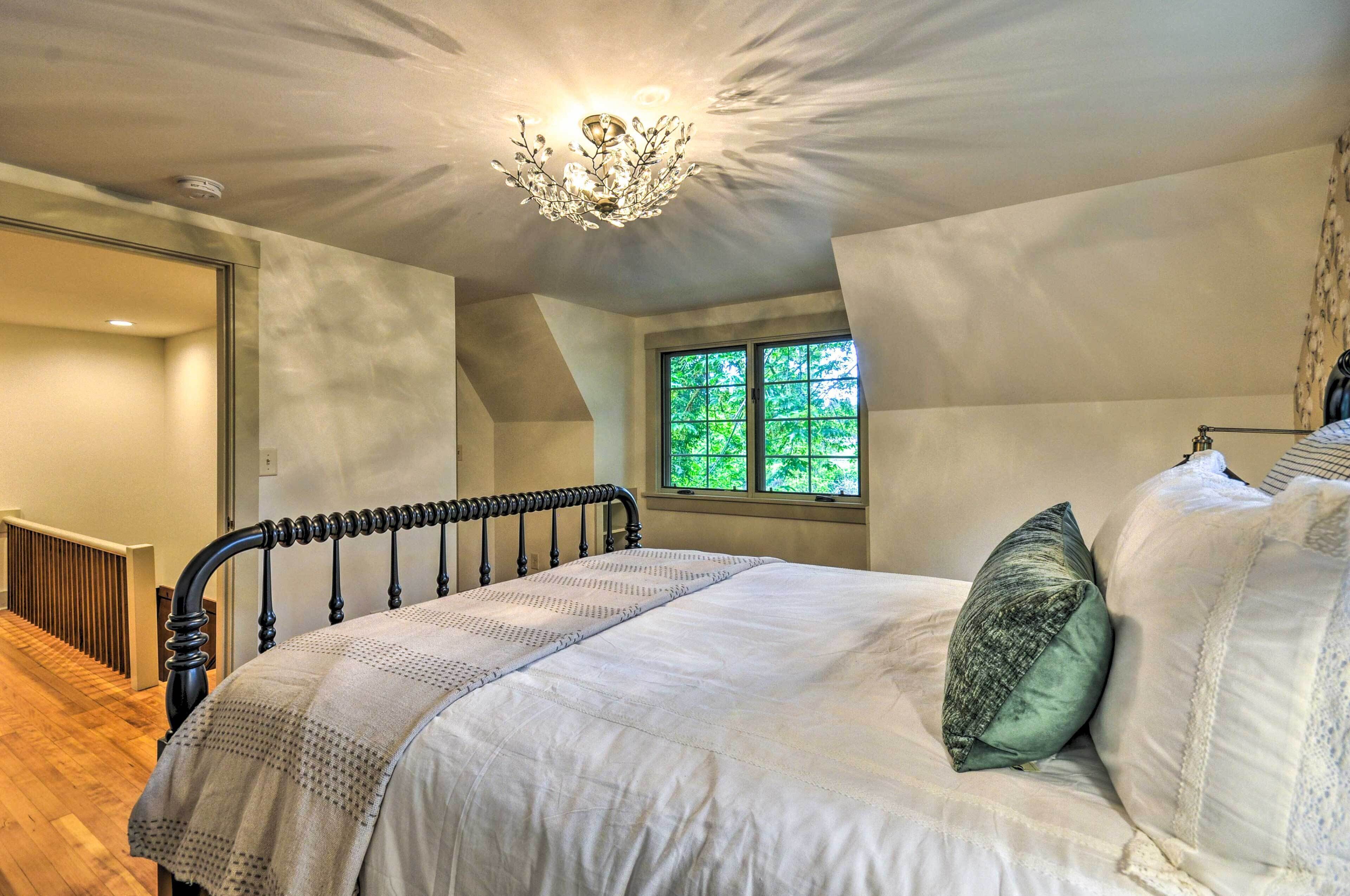 Ein Schlafzimmer mit einem Bett, einem Fenster mit Blick auf Grünflächen und einer Deckenleuchte.