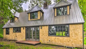 Ein zweistöckiges Haus mit Satteldach, großen Fenstern und einer Veranda.
