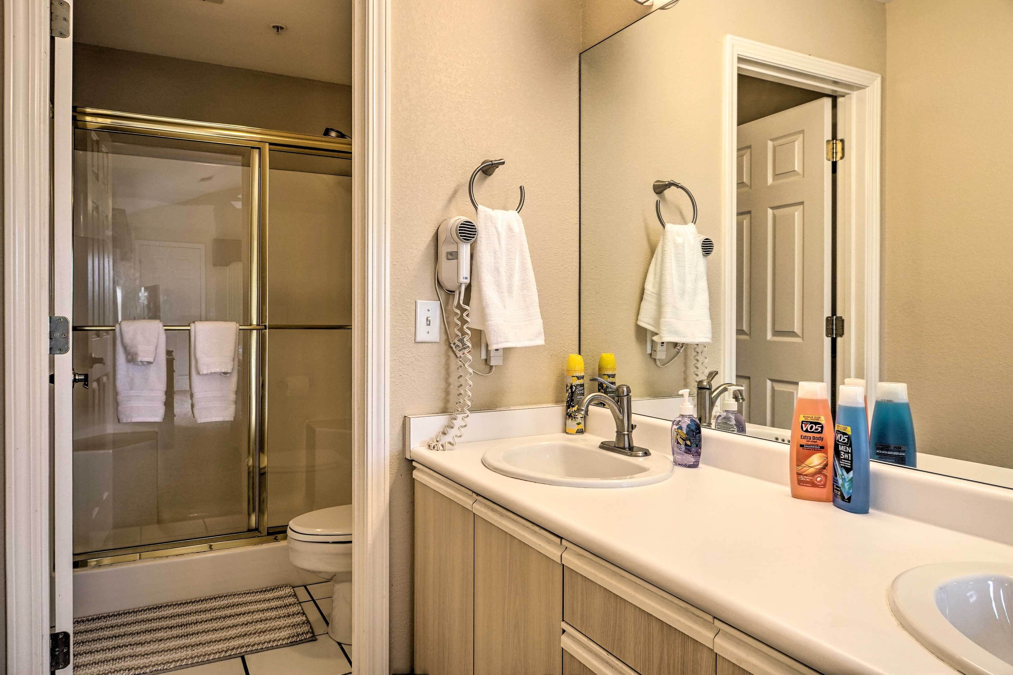 A bathroom with a glass shower, a sink, and a mirror.