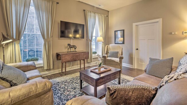 A living room with a sofa, armchair, coffee table, and a TV mounted on the wall. - Quaint Apartment in Historic Georgetown! (Georgetown)