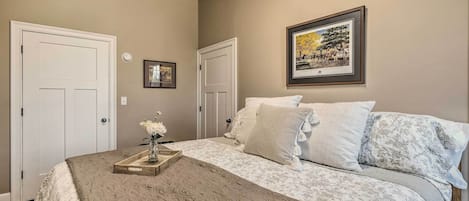 Un dormitorio ordenado con cama, mesita de noche con un florero y un cuadro en la pared.