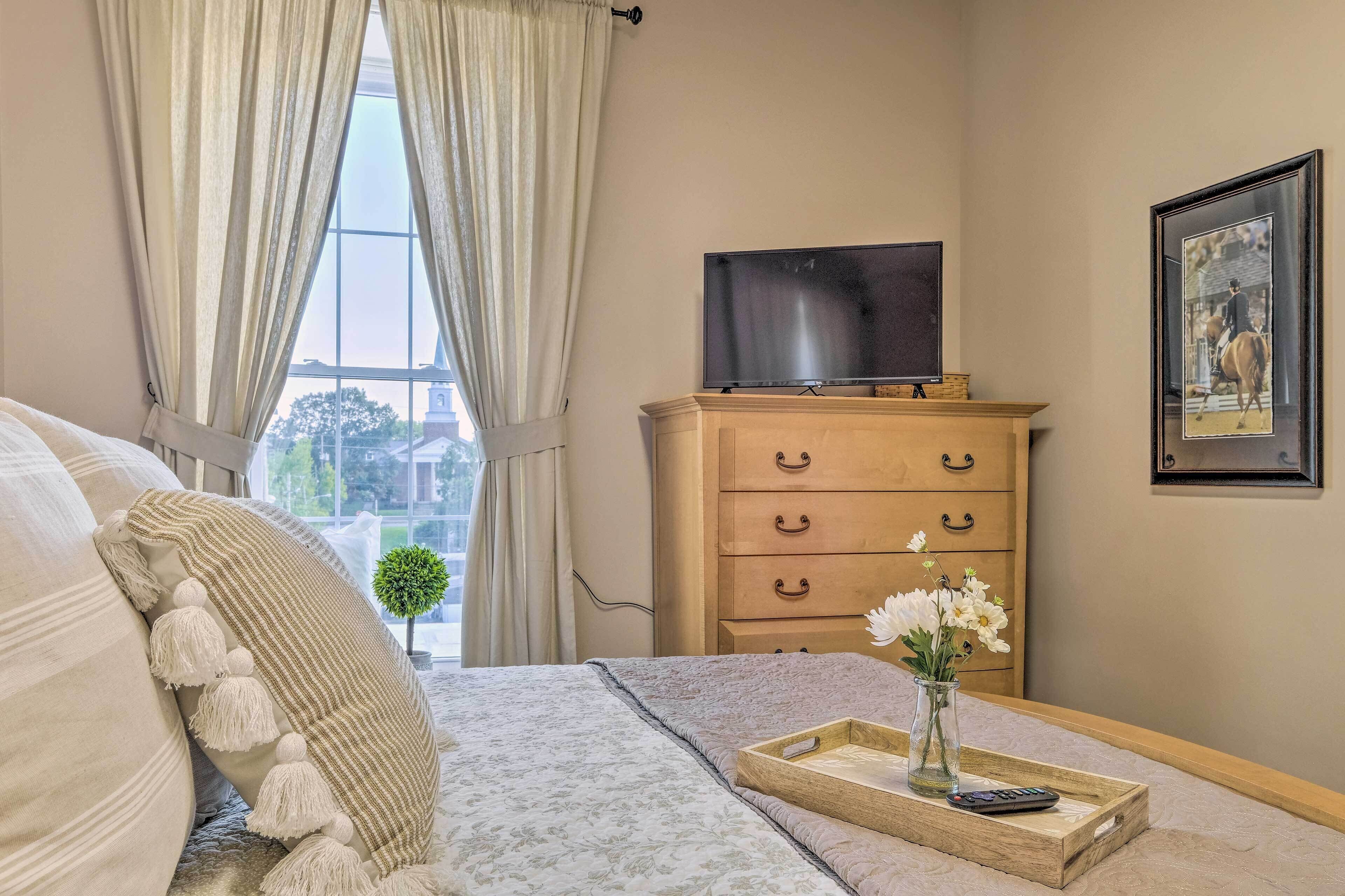 Une chambre à coucher avec un lit, une commode, un téléviseur et un tableau encadré au mur.