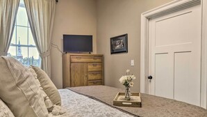 A bedroom with a bed, a dresser, a TV, a framed picture, and a door. - Quaint Apartment in Historic Georgetown! (Georgetown)