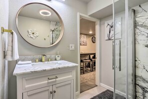 A bathroom with a marble sink, a large mirror, and a glass shower enclosure.