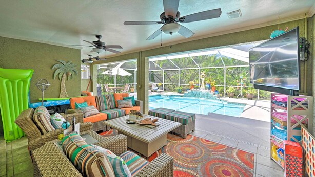 Ein geräumiger Wohnbereich mit Blick auf den Pool, Deckenventilatoren und einem Fernseher.