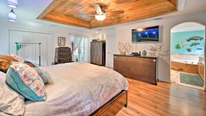 Ein Schlafzimmer mit Holzboden, einem Bett mit gemusterten Kissen, einem Schreibtisch und einem Fernseher.