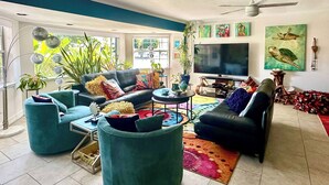 Ein modernes Wohnzimmer mit Türkis-Sofas, einem Flachbildfernseher und einem Deckenventilator.