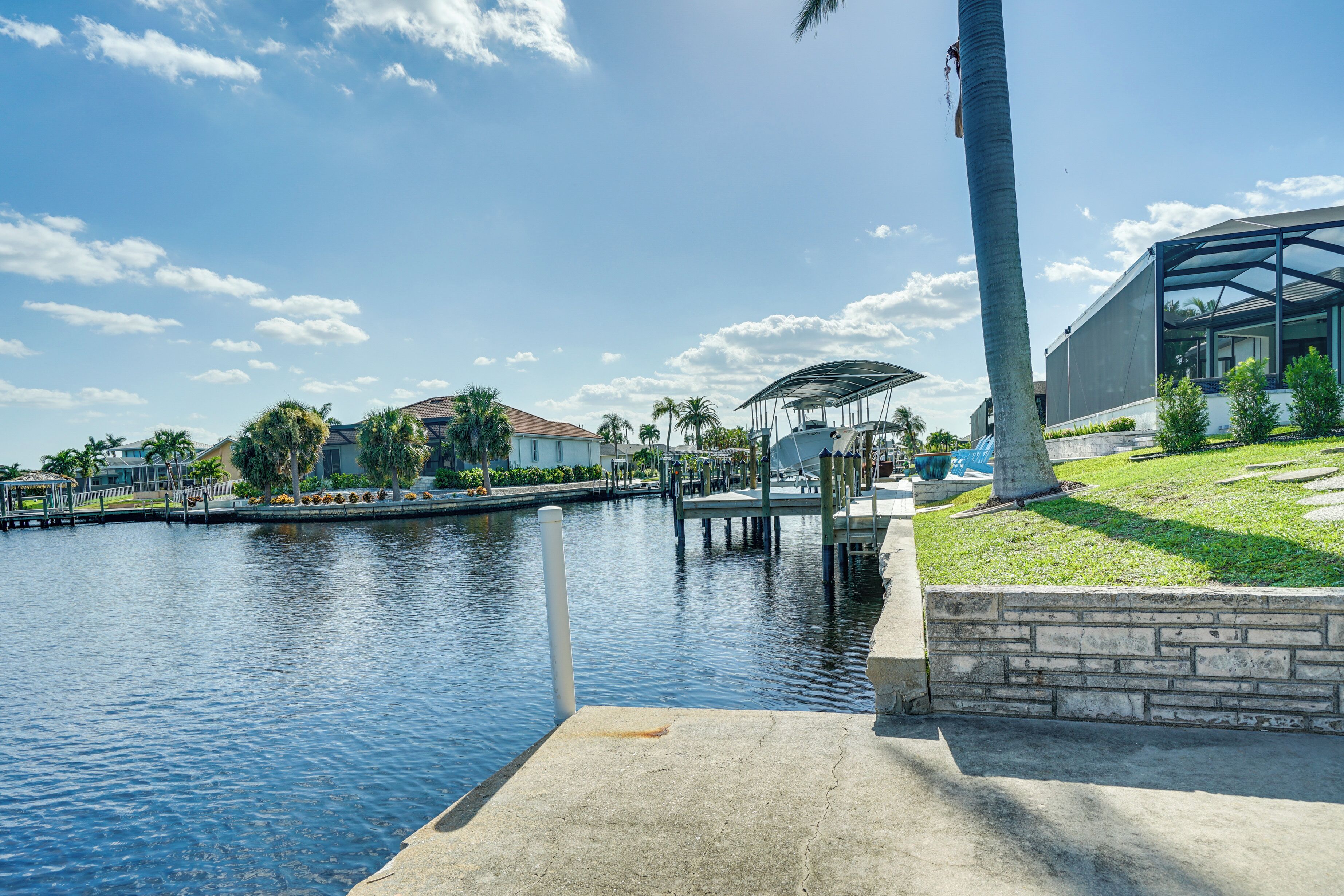 A waterfront property with a dock, a covered seating area, and a modern building with large windows.