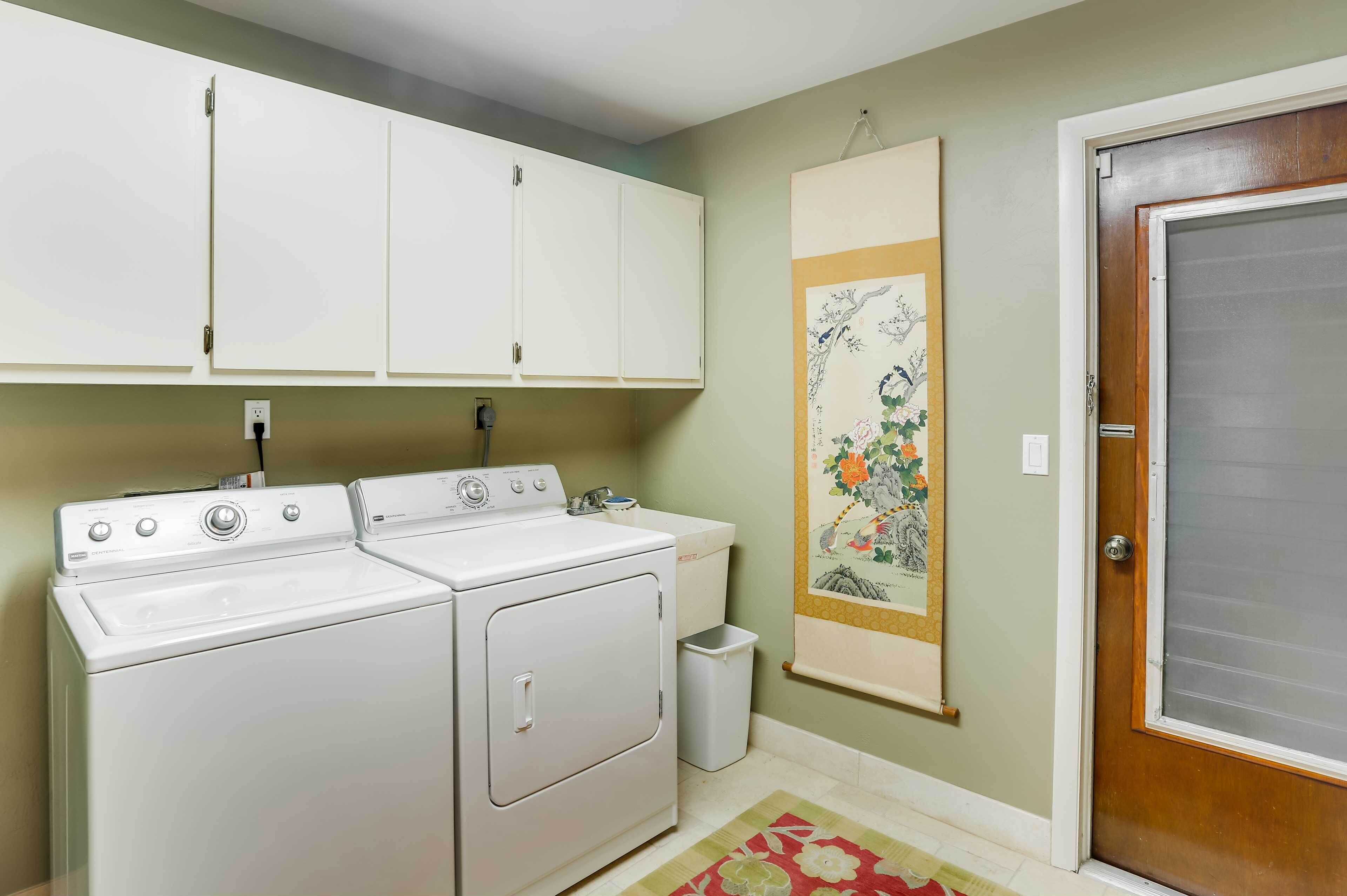 A laundry area with a washer and dryer, a trash can, and a door.