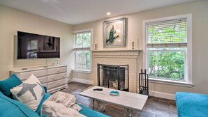 A living room with a fireplace, a television, and a sofa. - Renovated Ozona Home w/ Views - Steps to Gulf (Palm Harbor)
