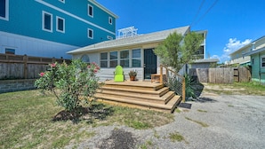 A residential building with a front porch, a small garden, and a wooden fence. - Bright Carolina Beach Cottage w/ Yard & Grill (Carolina Beach)
