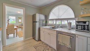A kitchen with a refrigerator, sink, and coffee maker. There is a dining area visible through an open door. - Bright Carolina Beach Cottage w/ Yard & Grill (Carolina Beach)