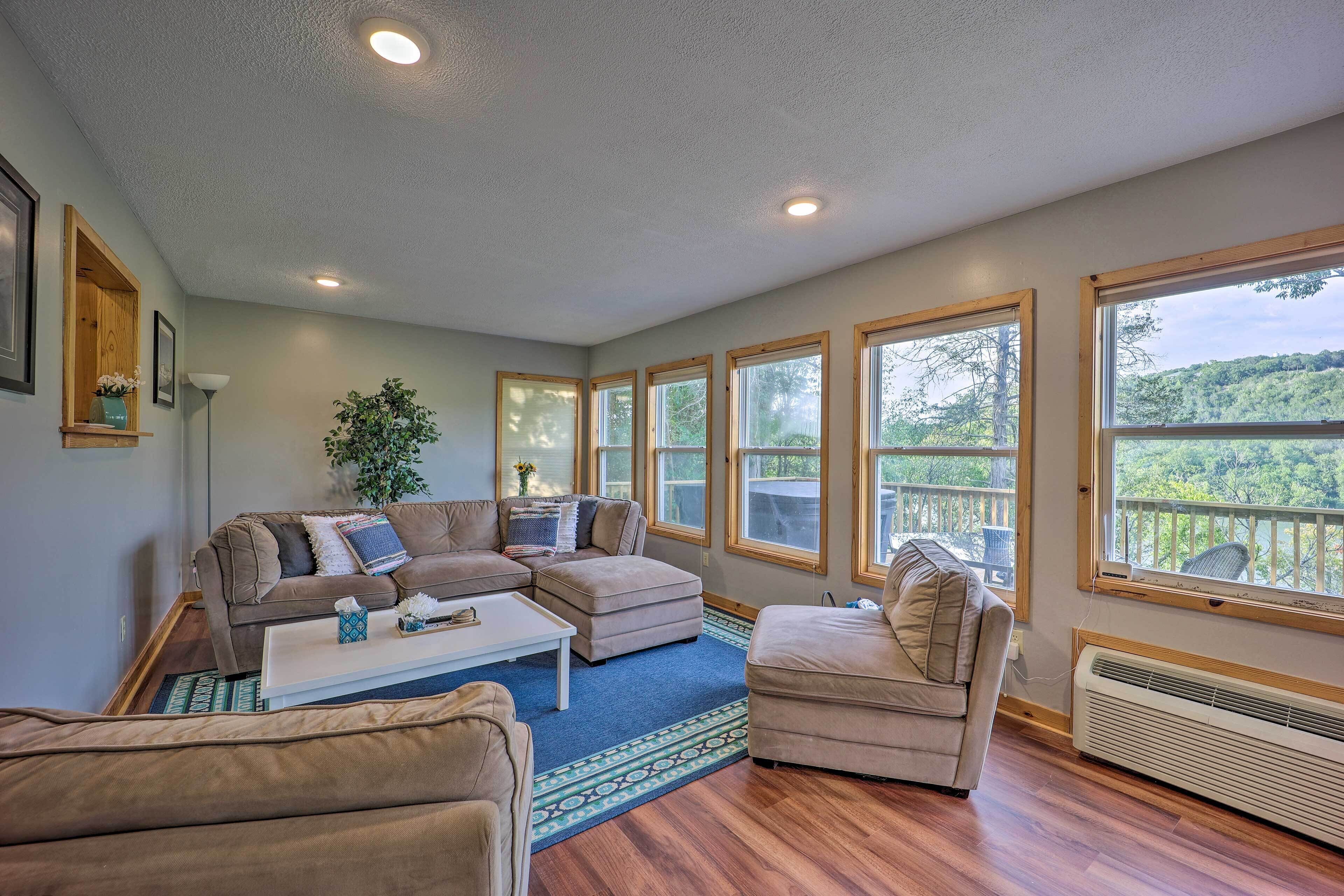 A spacious living room with a sectional sofa, a small coffee table, and a view of a balcony with a railing.