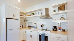 Une cuisine moderne avec des meubles blancs, une hotte en acier inoxydable et un plan de travail en bois.