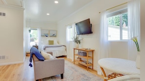 Un salon moderne avec un canapé, une petite table et un téléviseur fixé au mur.
