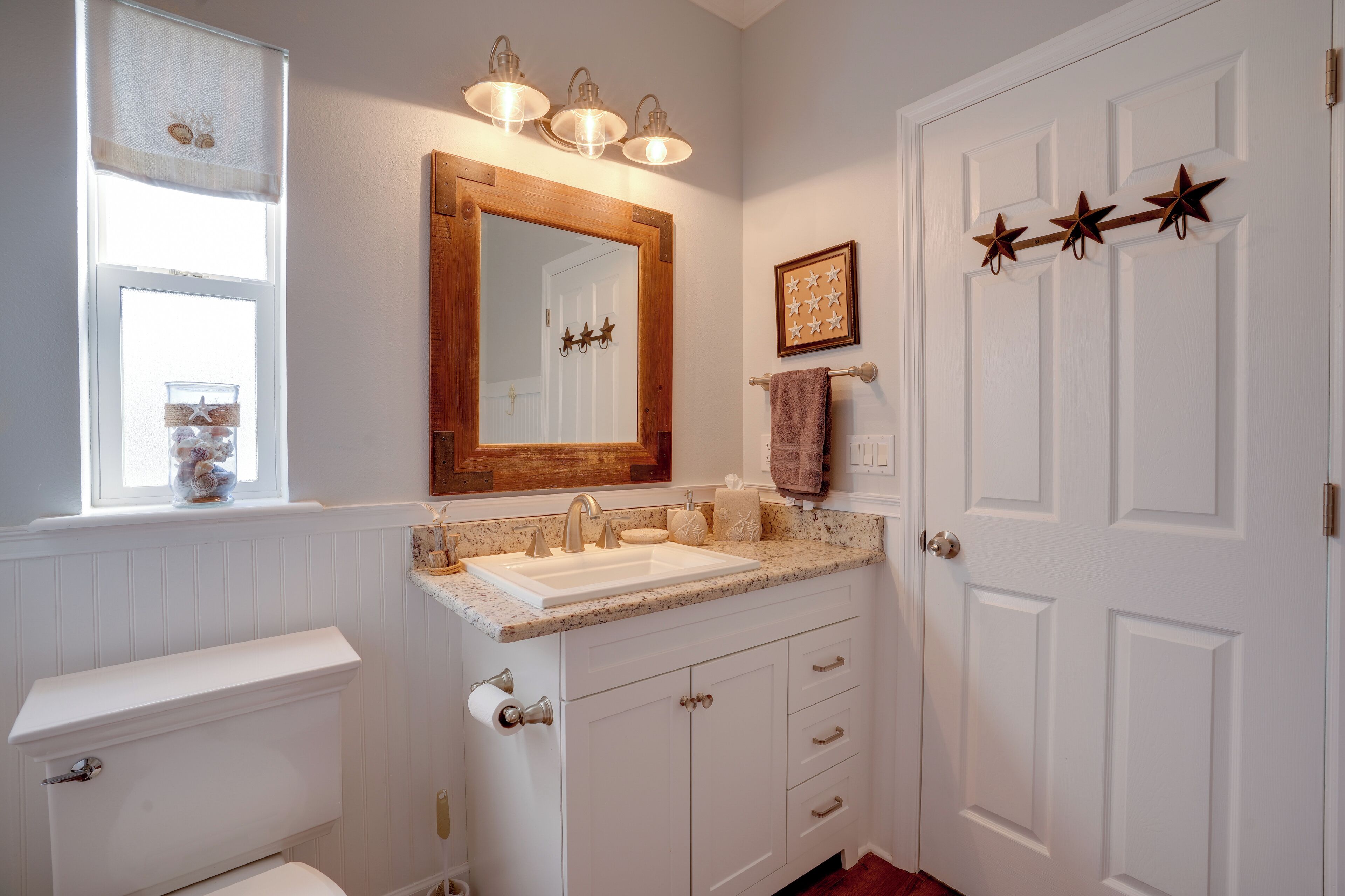 A bathroom with a white vanity, a large mirror, a sink, and a toilet.