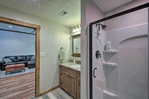 Bathroom features a large mirror, sink, and shower area with a glass door.