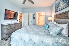 A bedroom with a bed, dresser, TV, and a door leading to a bathroom.