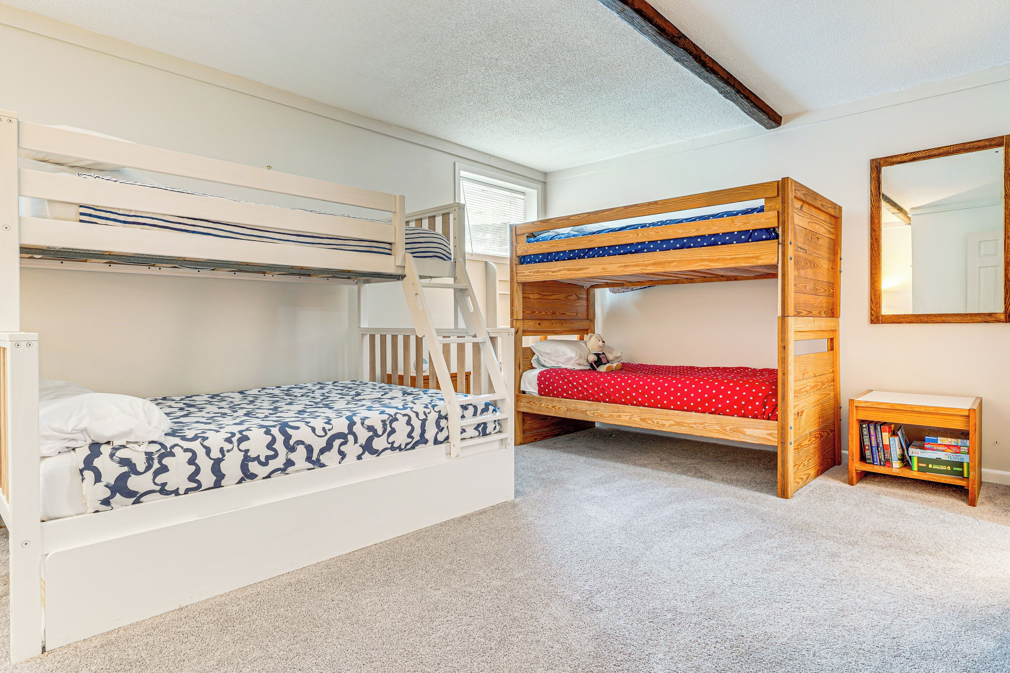Une chambre avec un lit superposé, une échelle en bois, une petite table en bois avec des livres et un miroir au mur.