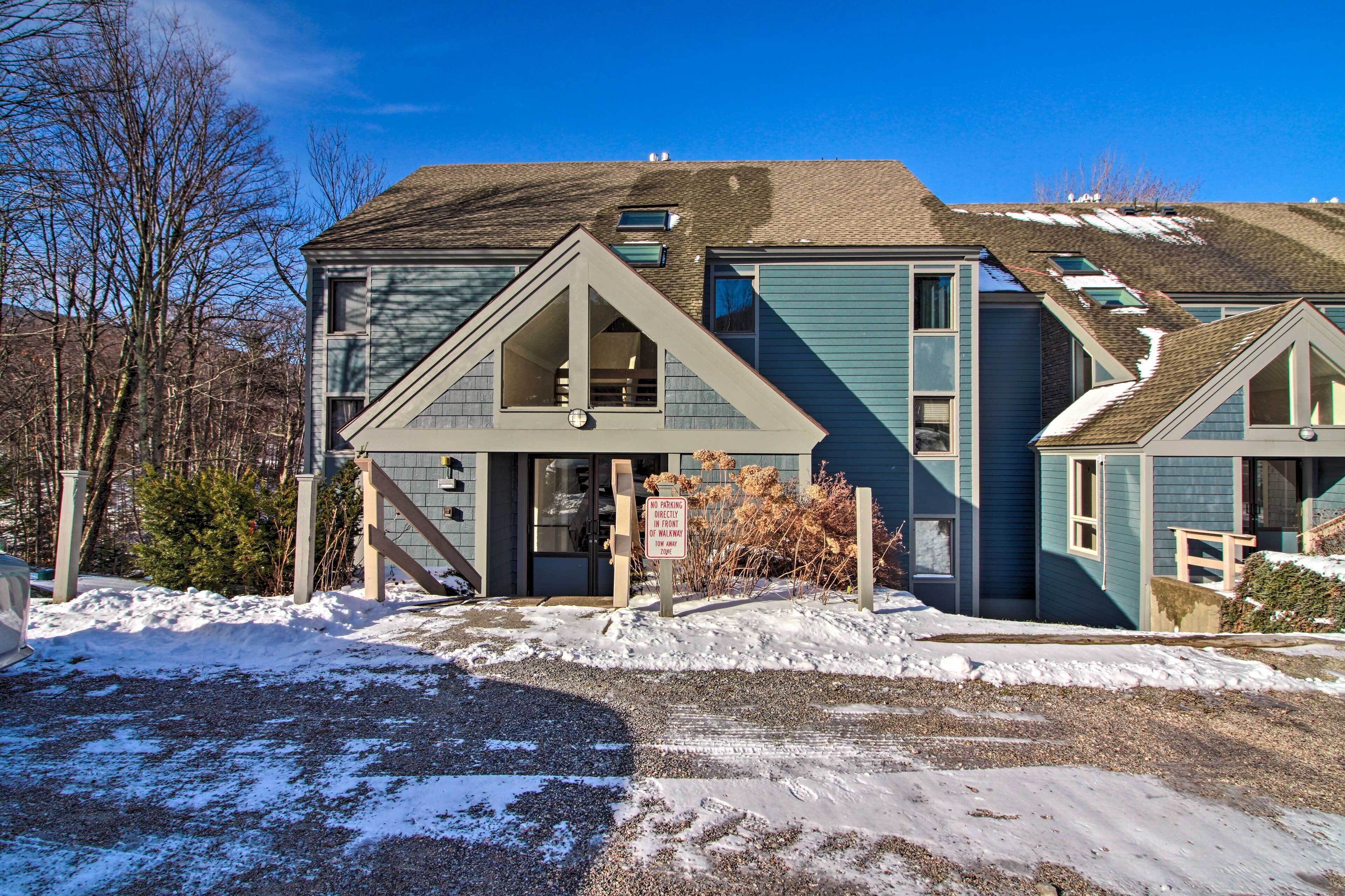 A two-story house with a front porch, a garage, and a snow-covered driveway.