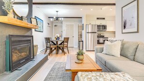 A modern living room with a fireplace, a dining area, and a kitchen with stainless steel appliances. - Ski-home Trail: Updated Killington Condo (Killington)