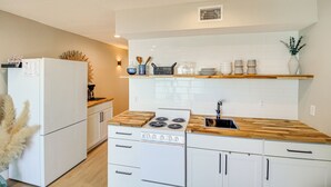 Une cuisine moderne avec des meubles blancs, un plan de travail en bois et une cuisinière intégrée.