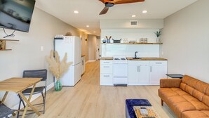 Une cuisine moderne avec des armoires blanches, un plan de travail en bois et un ventilateur de plafond.
