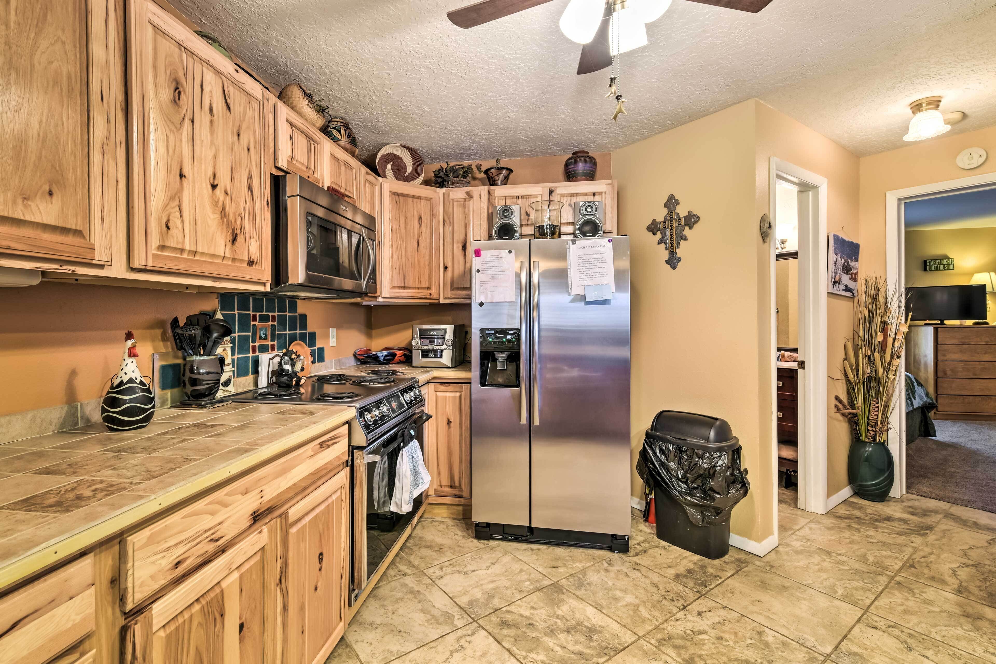 A kitchen with wooden cabinets, a stainless steel refrigerator, a microwave, and a stove.