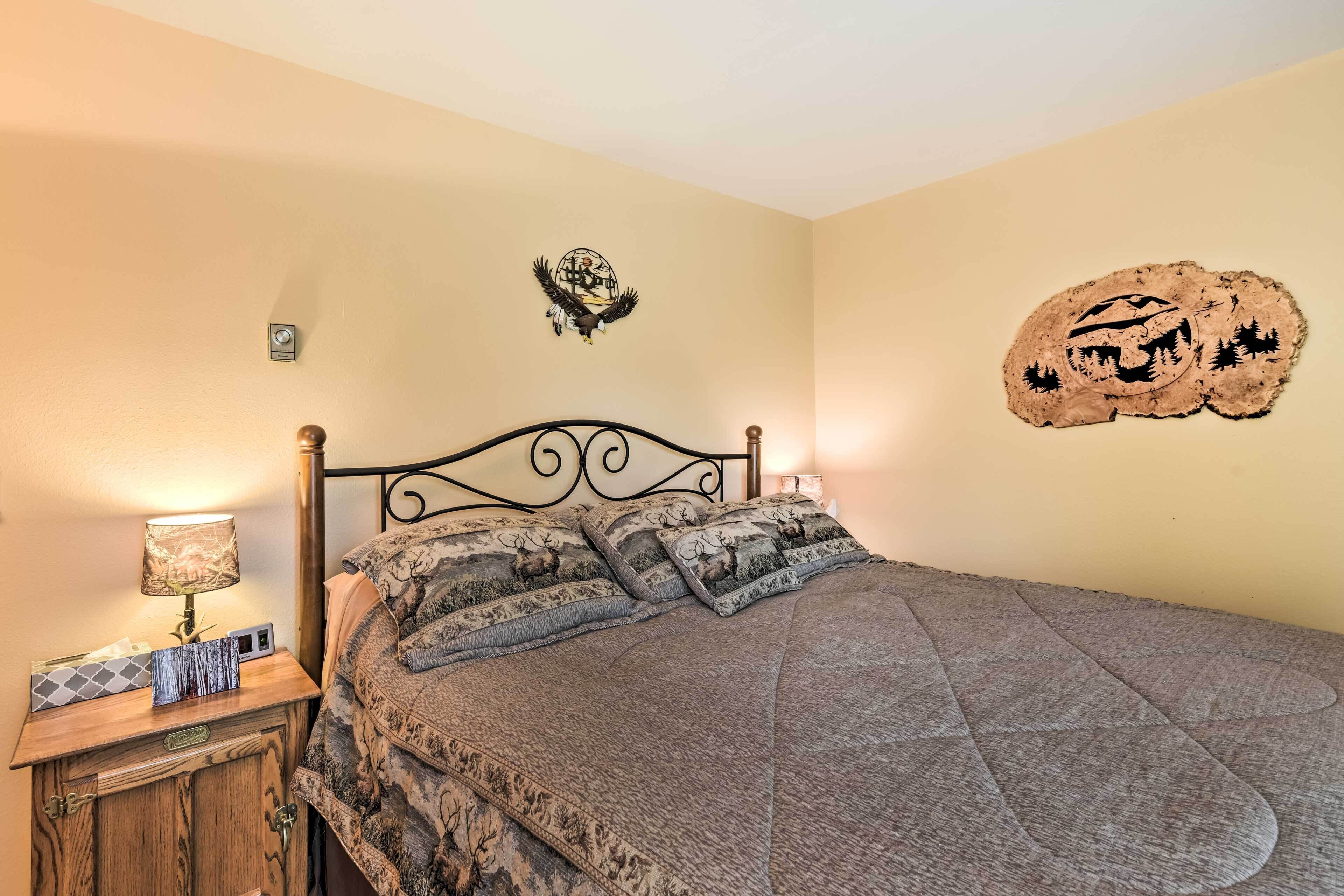 A bedroom with a bed, nightstand, lamp, and decorative wall art.