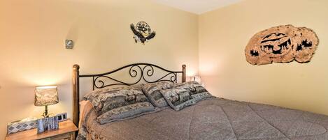 A bedroom with a bed, nightstand, lamp, and decorative wall art.
