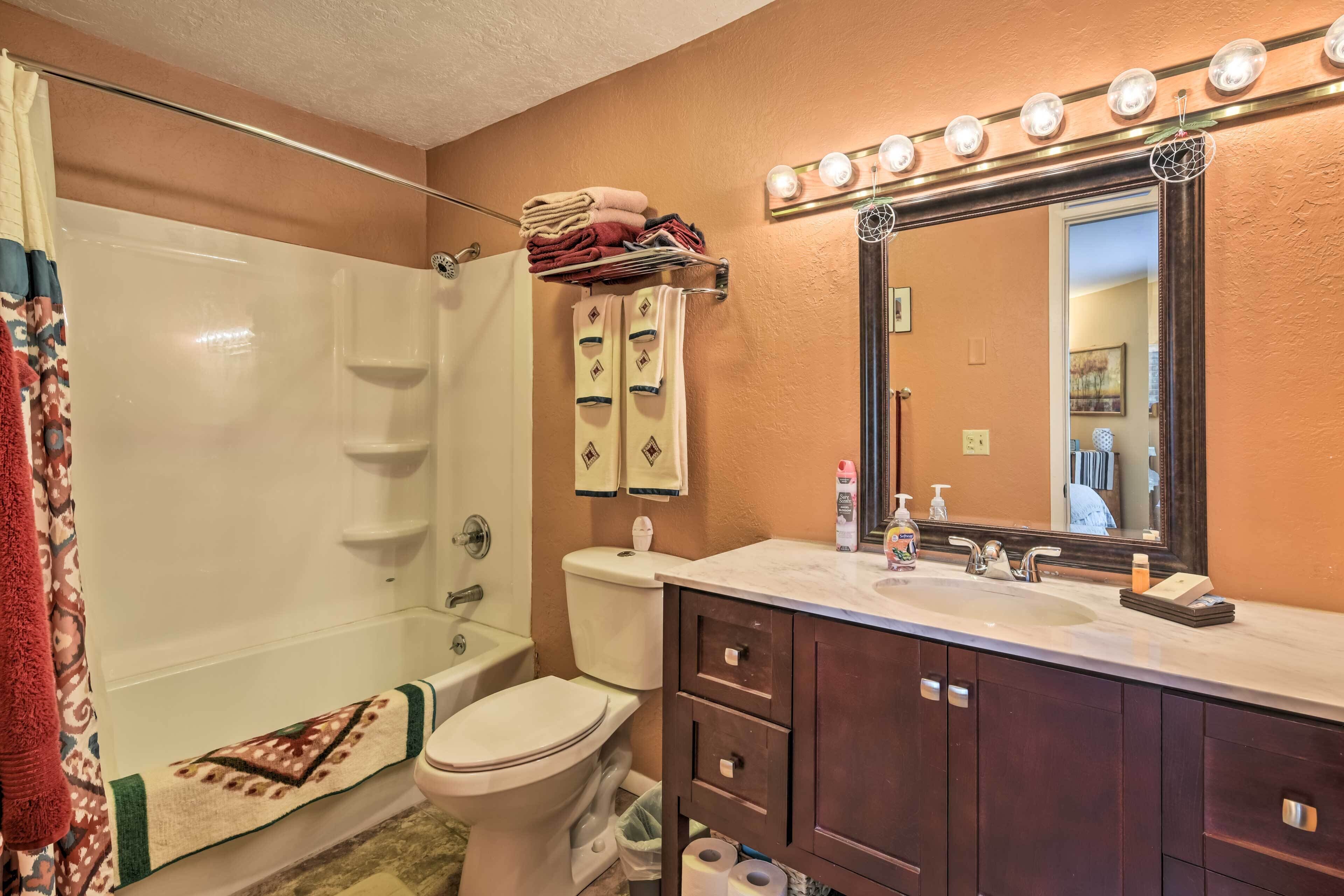 A bathroom with a bathtub, toilet, vanity with a mirror, and a towel rack.