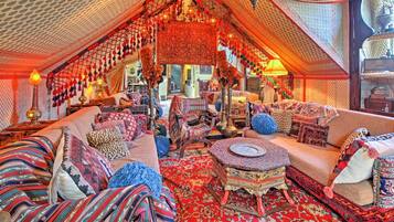 A cozy, well-decorated room with a large sofa, patterned rugs, and a variety of seating options.